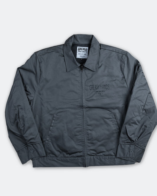 steel gray mechanic jacket with greasy hands society TX - text on the front left chest n a white background