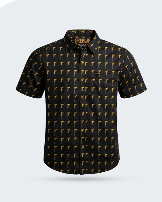 A short-sleeve button-up shirt by The Rebel, featuring a black base with a repeating yellow pistol pattern, displayed on a light gray background - The Hitman Button-Up Shirt by Greasy Hands Society