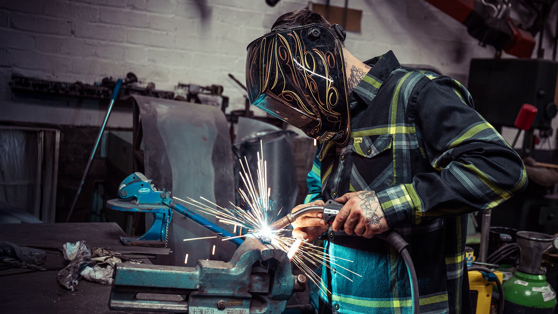 eat dusman wearing the eat dust black gray and yellow flannel while welding with his visor down