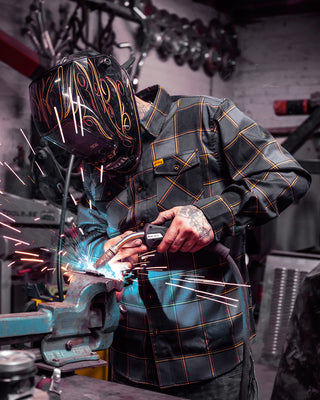 el lobo gray and orange flannel on a welder laying down dimes - main image
