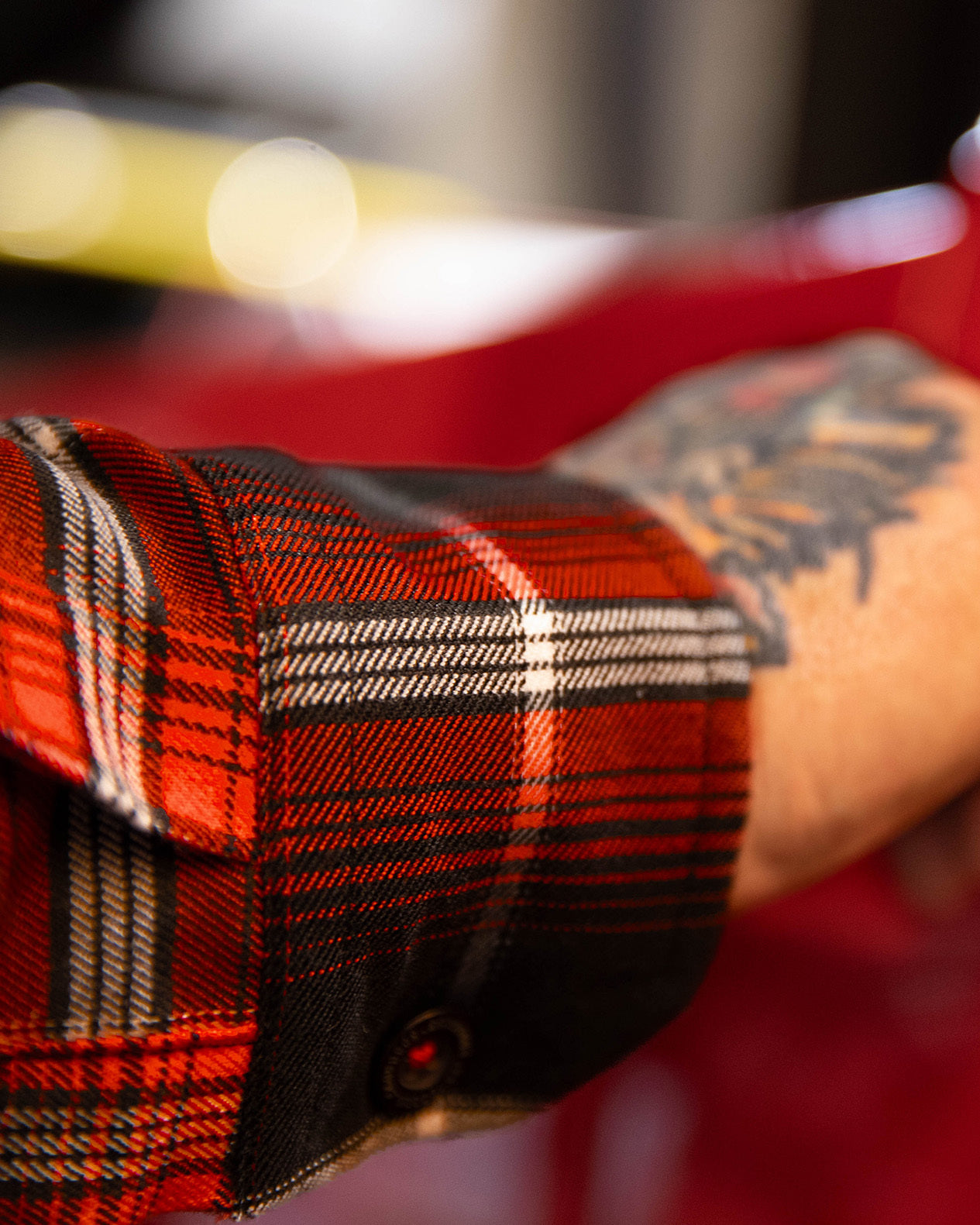 Close-up of a person wearing a red plaid shirt with a blurred background