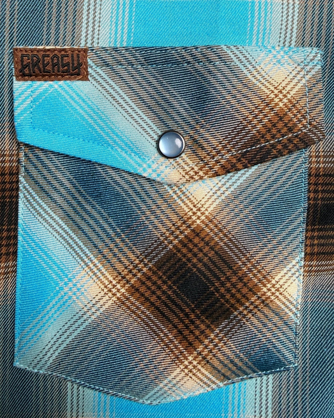 Plaid pocket on a garment with a brand label, featuring blue and brown colors - Cold Start Flannel by Greasy Hands Society