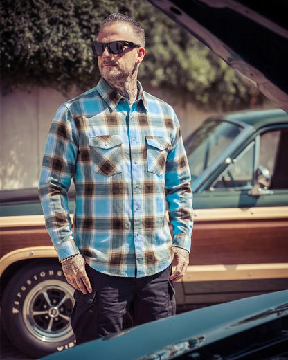 Man wearing a plaid blue and brown flannel shirt and sunglasses standing next to a vintage truck - Cold Start Flannel by Greasy Hands Society