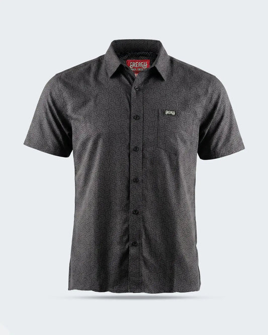 A dark gray short-sleeve button-up shirt with a subtle textured pattern, featuring a chest pocket with a small green logo on the left chest, displayed on a light gray background - The Burnout Button-Up Shirt by Greasy Hands Society