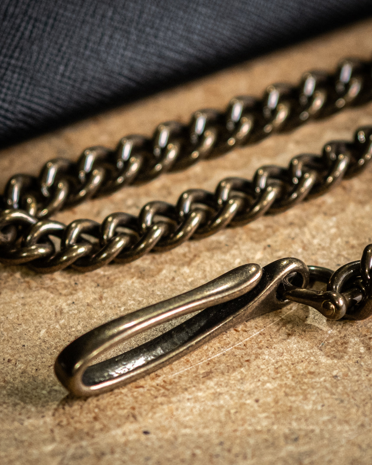 Brass chain necklace with clasp on a textured surface - Brown leather wallet by Greasy Hands Society