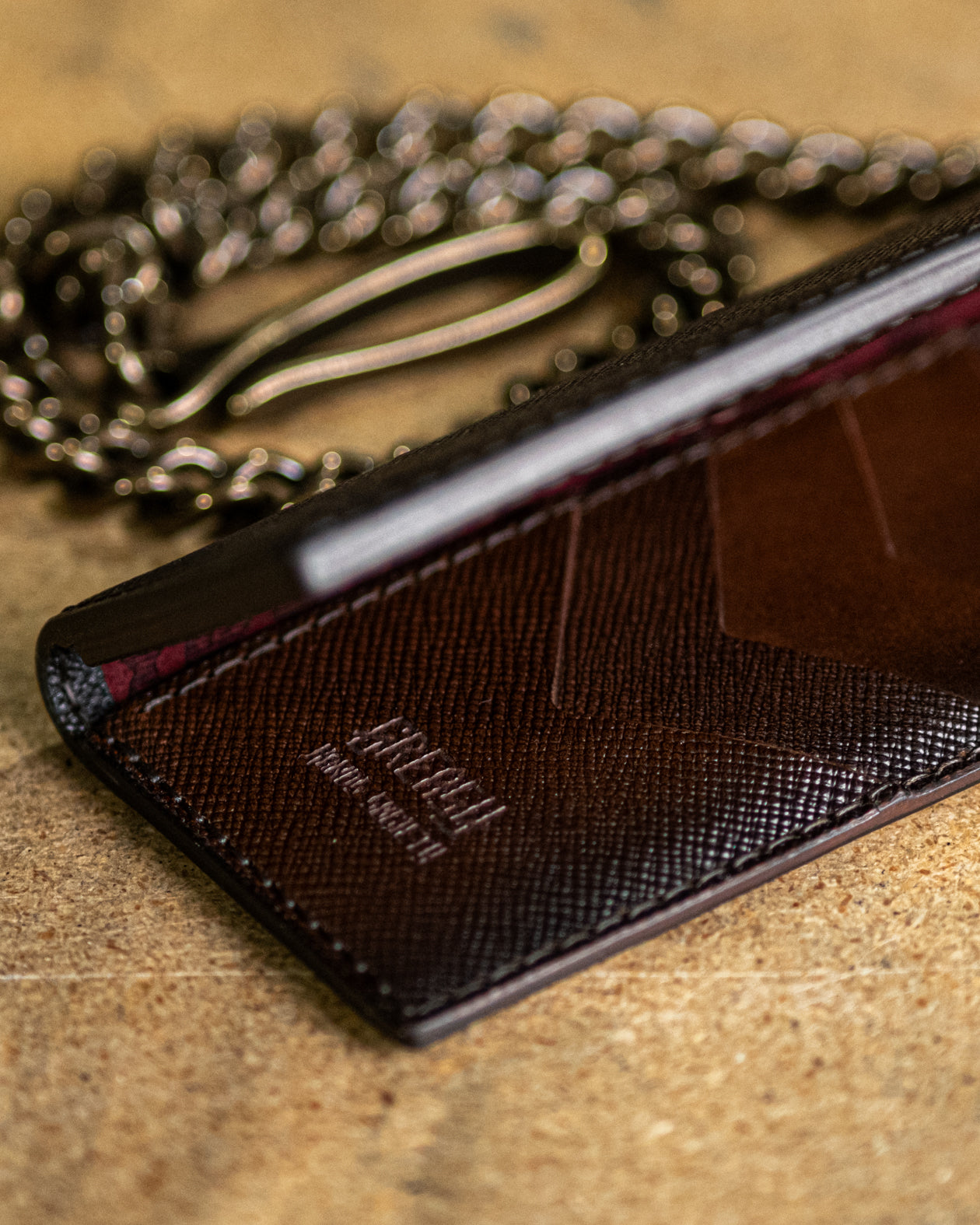 vertical black leather wallet with chain on a textured surface