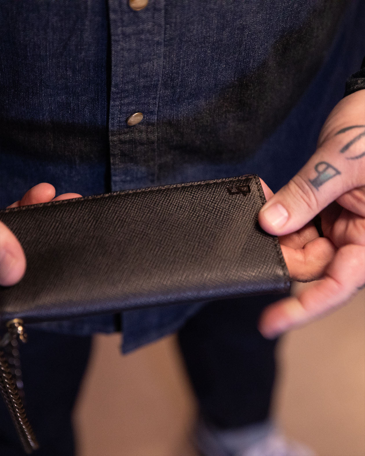 Person holding a greasy hands society black wallet with a blurred background
