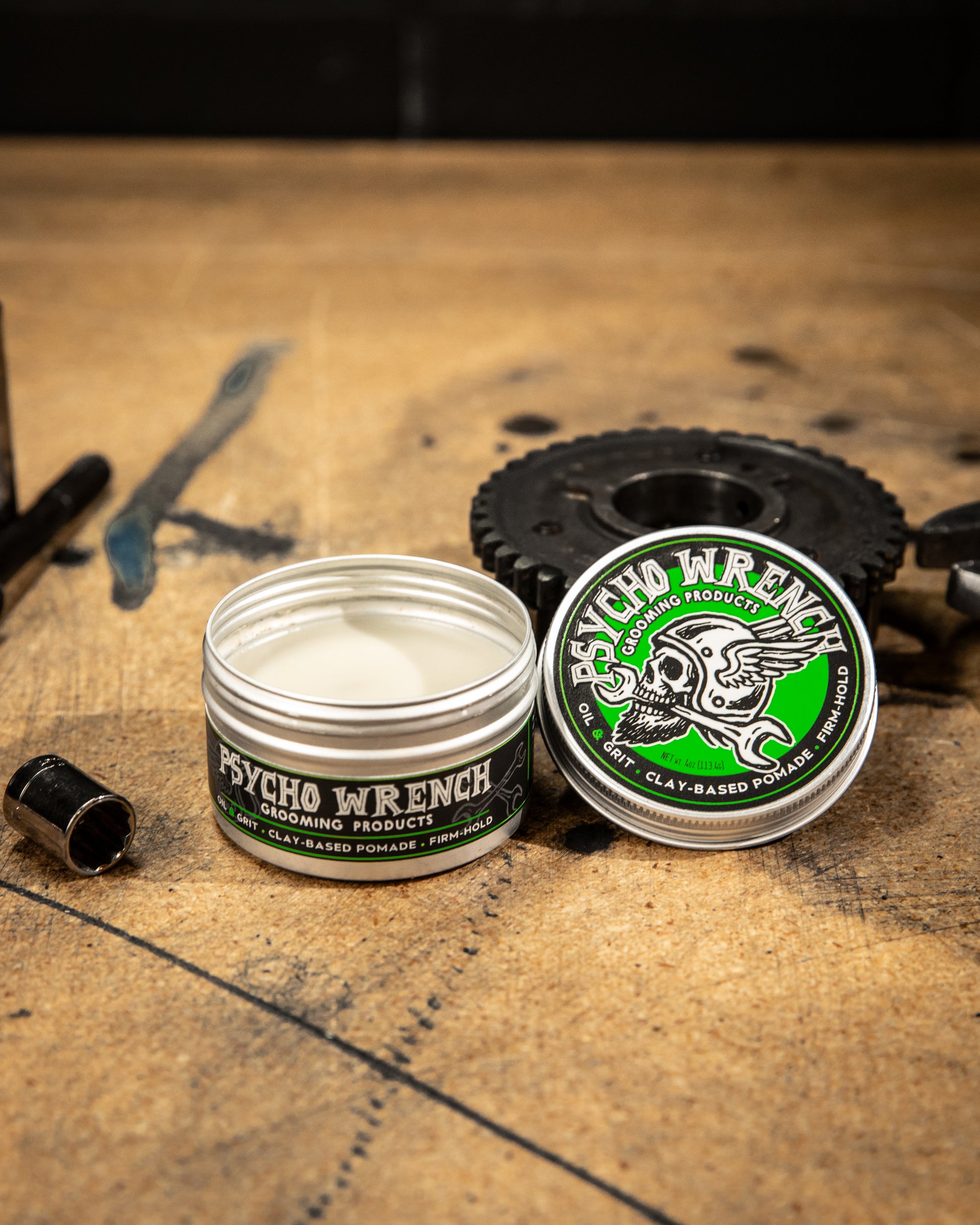 container of Psycho Wrench grooming product clay based pomade on a rustic wooden surface