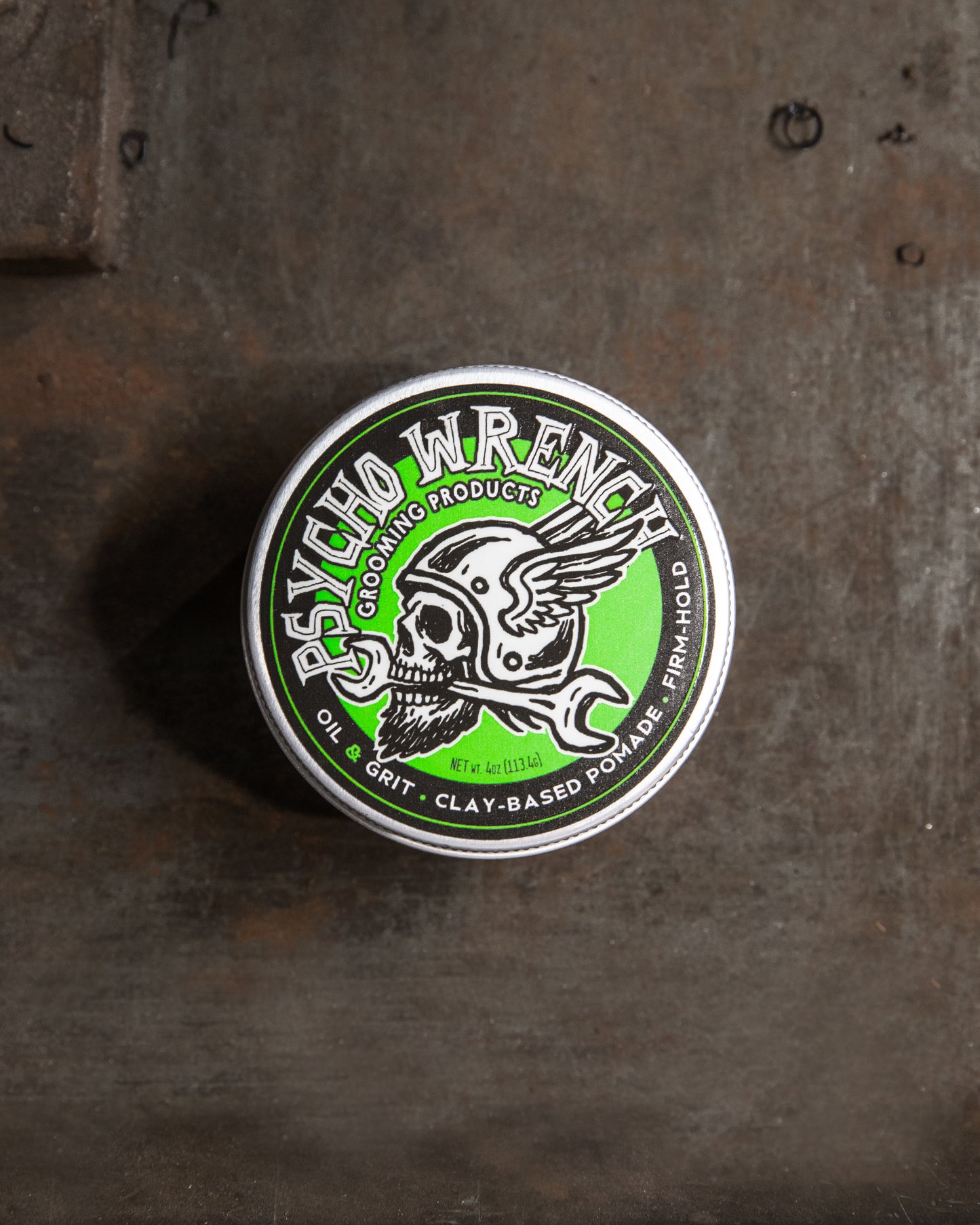 clay-based Pomade container with 'Psycho Wrench' branding on a textured surface