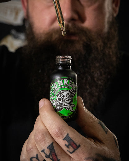 Person holding a bottle labeled 'Psych Wrench gooming products beard oil' with a dropper close to the bottle.