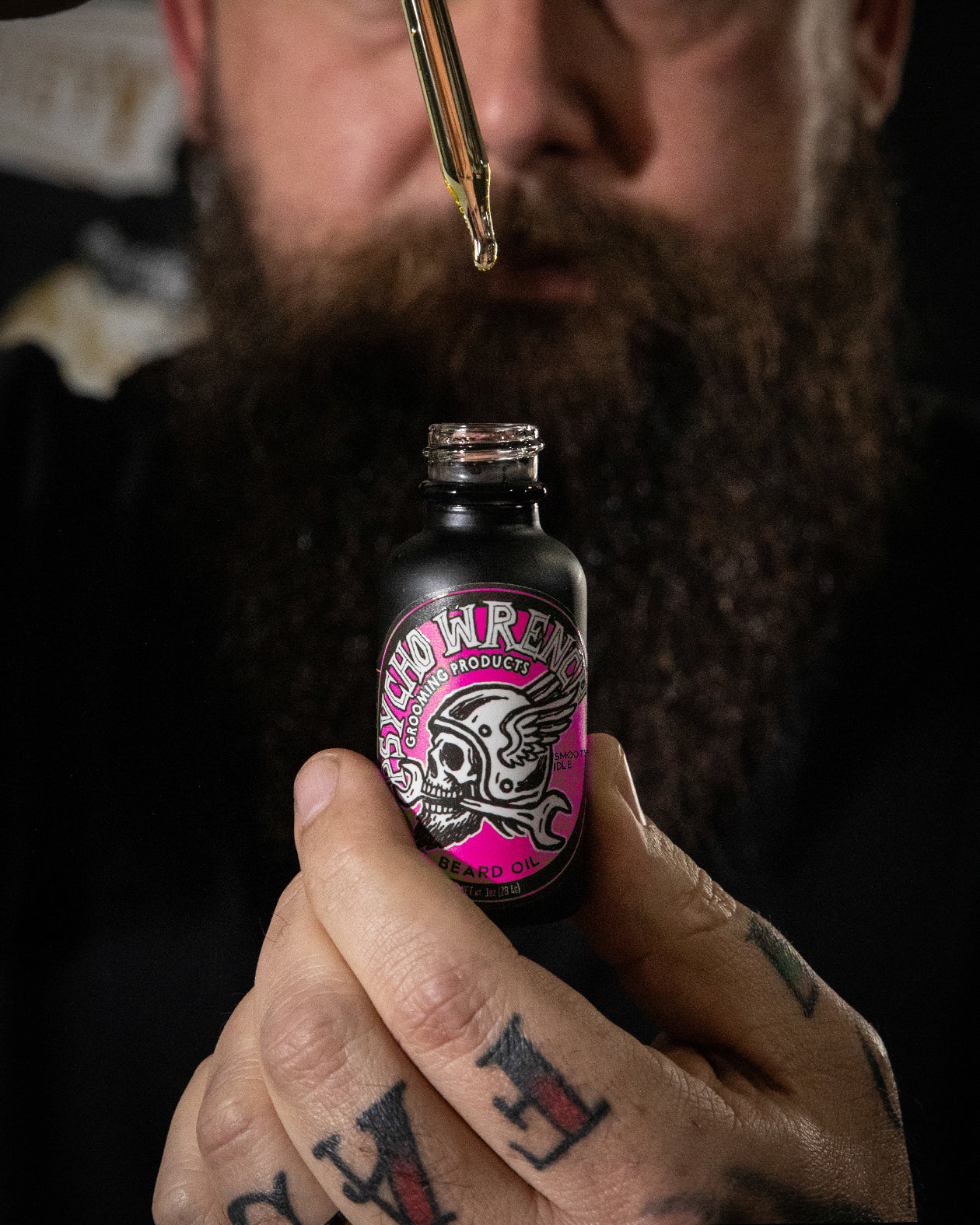 person holding a bottle of psycho wrench beard oil with smooth idle scent