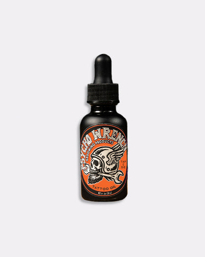 Black bottle of Psycho Wrench beard oil with orange label on a white background - Psycho Wrench Tap & Die Tattoo Oil by Greasy Hands Society