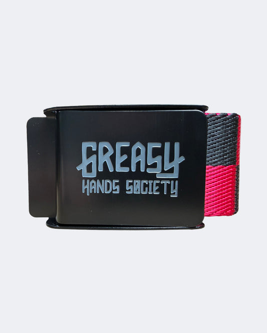 A black belt buckle featuring the 'Greasy Hands Society' logo in a stylized silver font, with a woven strap showing black and pink sections, set against a light gray background -Pink Noise Belt by Greasy Hands Society