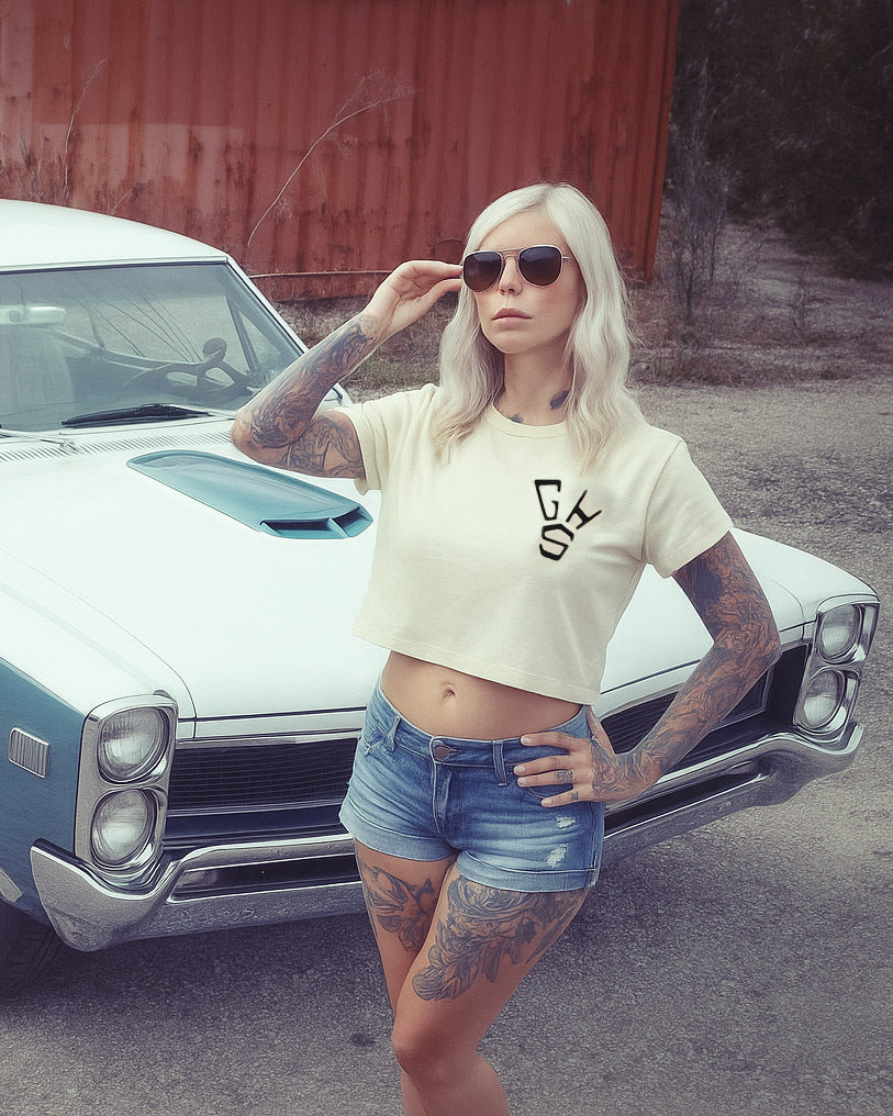 women's well balanced grpahic crop top t-shirt - Woman posing in front of a classic car wearing a crop top with a logo and denim shorts.