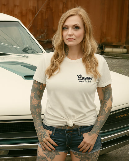 womens' destination graphic tee in vintage white - Woman wearing a white t-shirt with 'Greasy Hands Society' text in front of a vintage car.