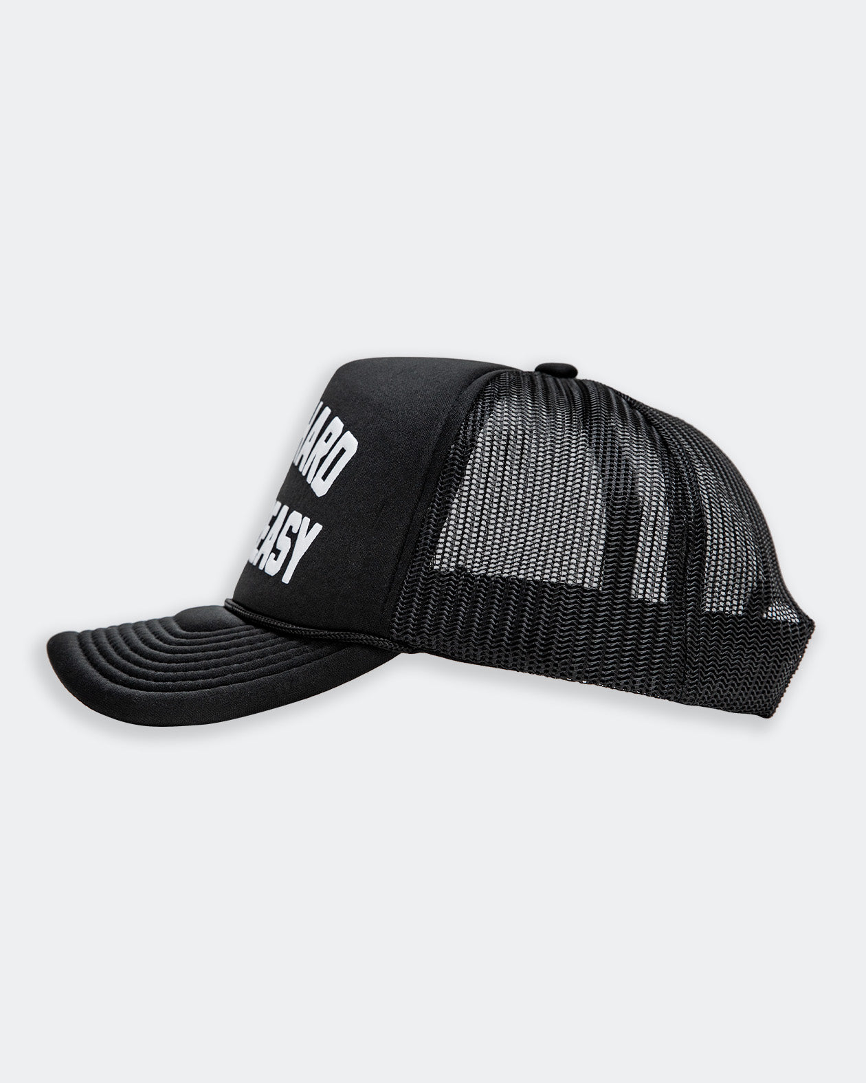 work hard stay greasy black  foam trucker hat with white text side view on a gray background
