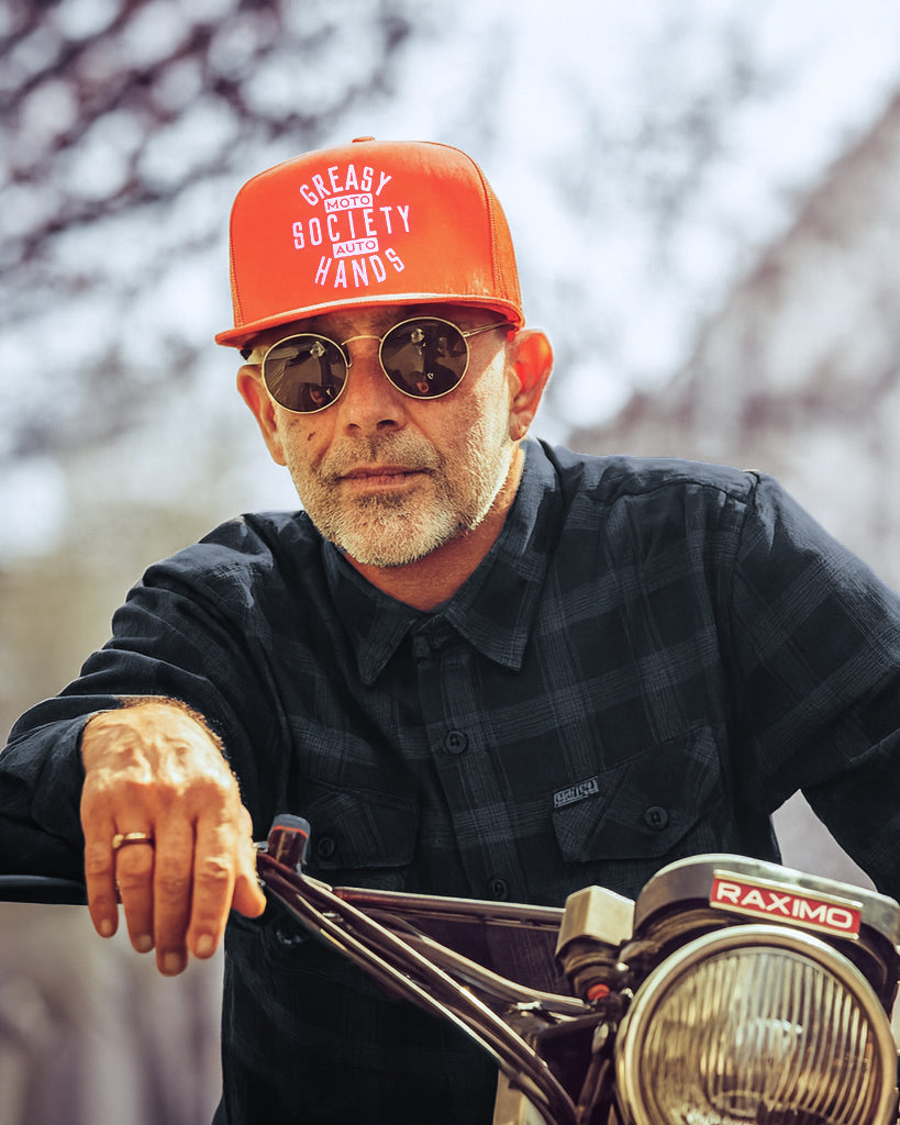 orange station hat - orange trucker hat by greasy hands society being worn by a man on a motorcycle 