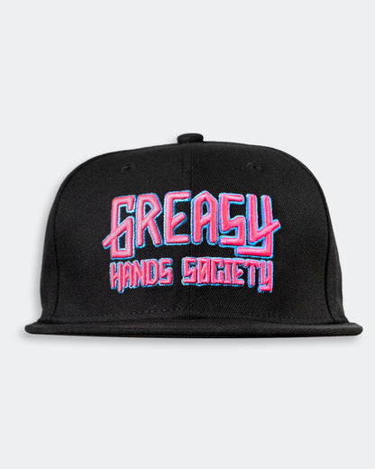 Black cap with pink and blue 'Greasy Hands Society' logo on a light gray background