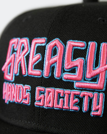 detail shot of a black cap with pink and blue greasy hands society logo on the front - showing the stitching