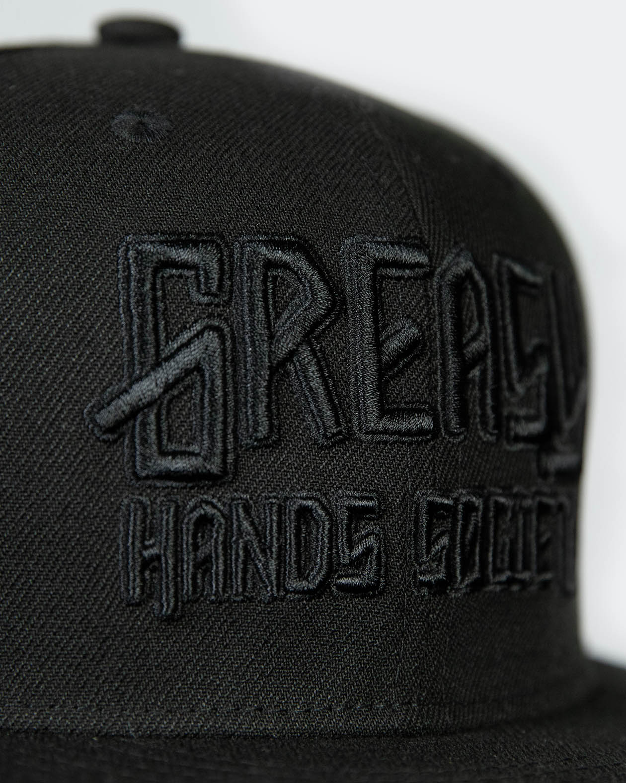 detail shot of a black cap with black greasy hands society logo on the front - showing the stitching