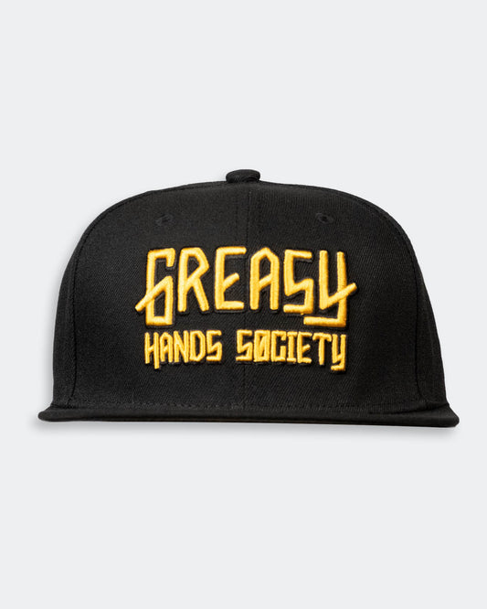 Black cap with gold 'Greasy Hands Society' logo on a light gray background