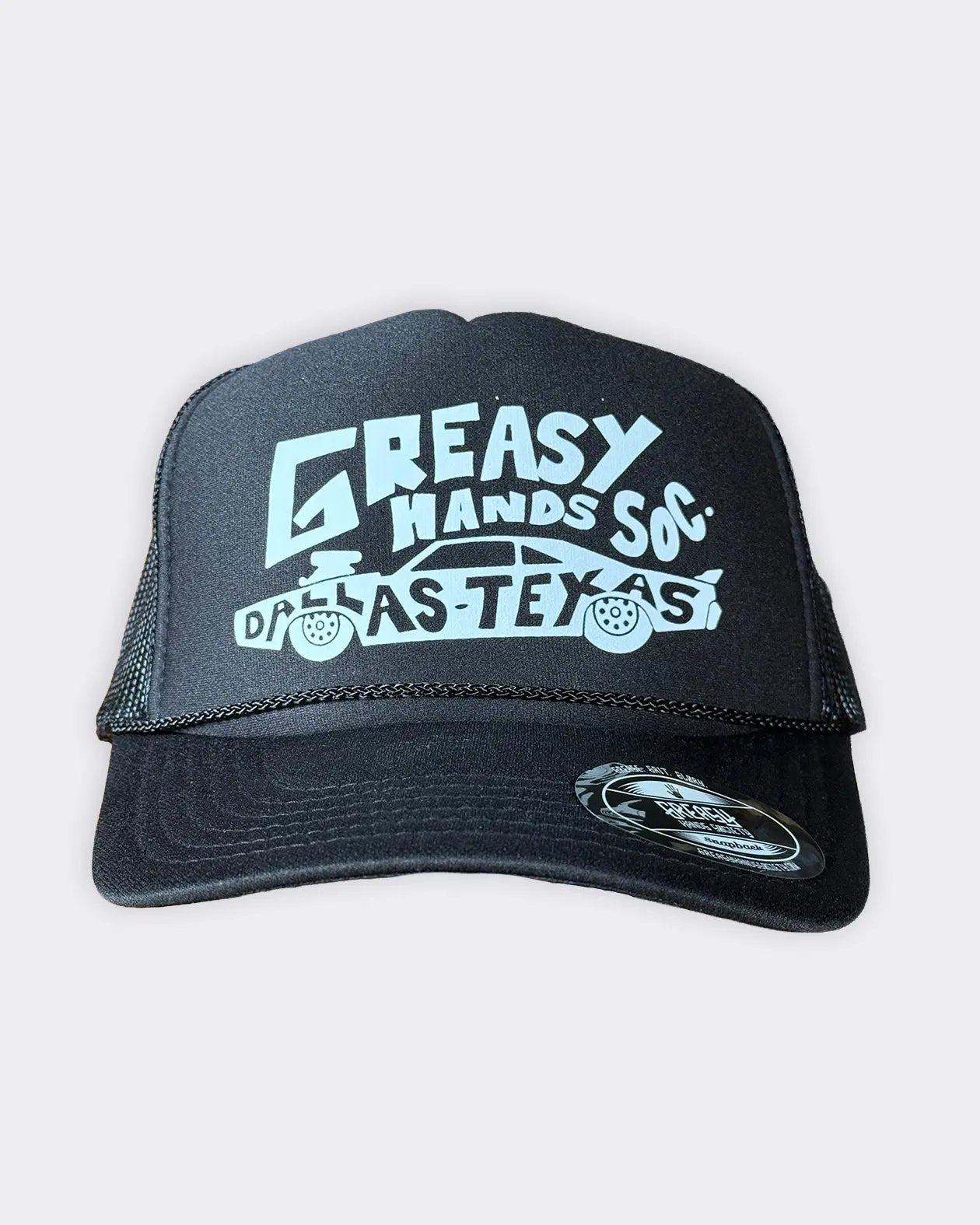 A black trucker hat with a white graphic print reading 'GREASY HANDS SOX' and 'DALLAS TEXAS' with a car illustration, shown against a light gray background - Dallas Dragster Black/White Hat by Greasy Hands Society