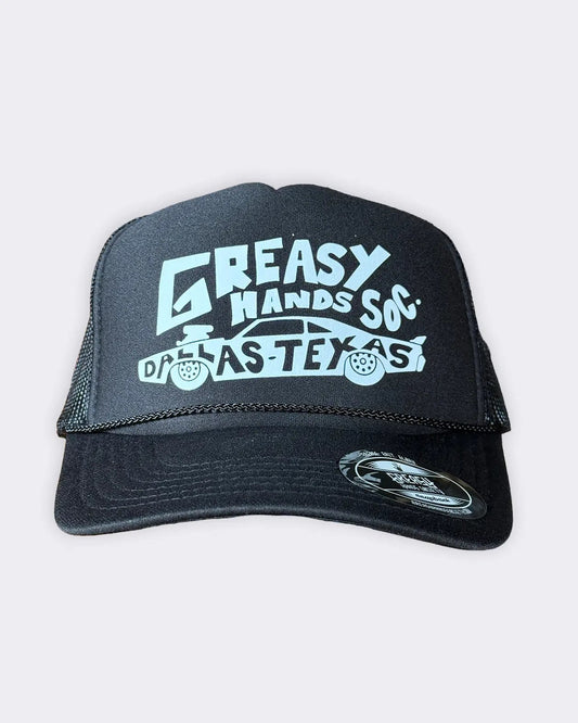A black trucker hat with a white graphic print reading 'GREASY HANDS SOX' and 'DALLAS TEXAS' with a car illustration, shown against a light gray background - Dallas Dragster Black/White Hat by Greasy Hands Society