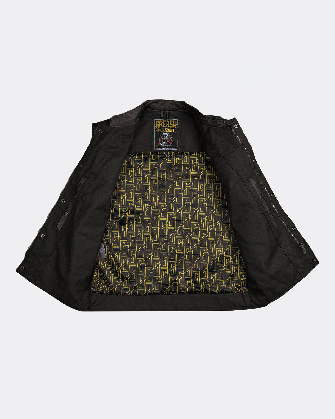 Black leather and canvas vest with a patterned interior of the greasy hands society "G" on a light gray background