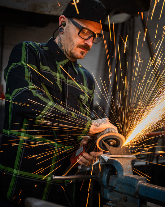 Person wearing a black and green plaid flannel shirt with a blurred background while grinding