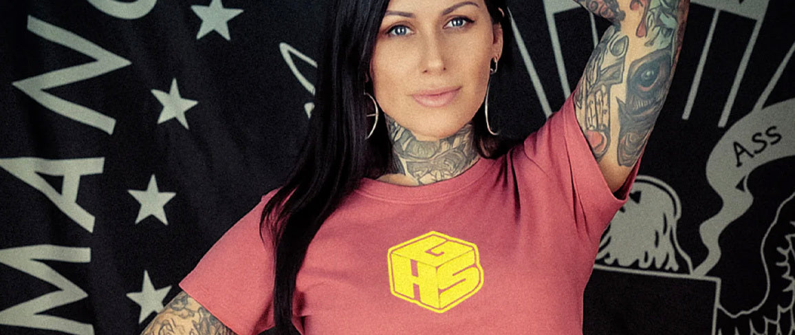woman wearing a peach t-shirt with a yellow logo against a black flag background