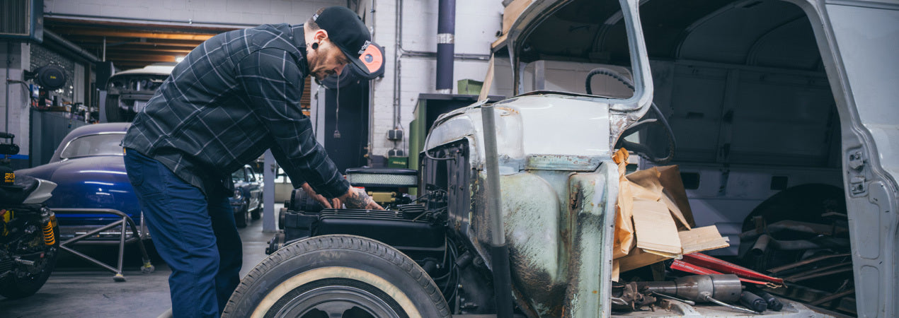 Person working on an old classic car in a garage  and wearing a gray plaid flannel shirt - The Dapper Flannel by Greasy Hands Society