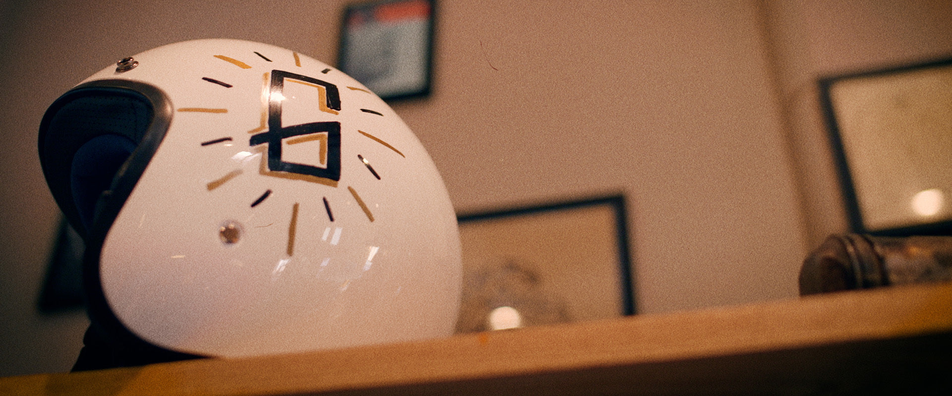 White vintage motorcycle helmet with a logo on a shelf against a blurred indoor background