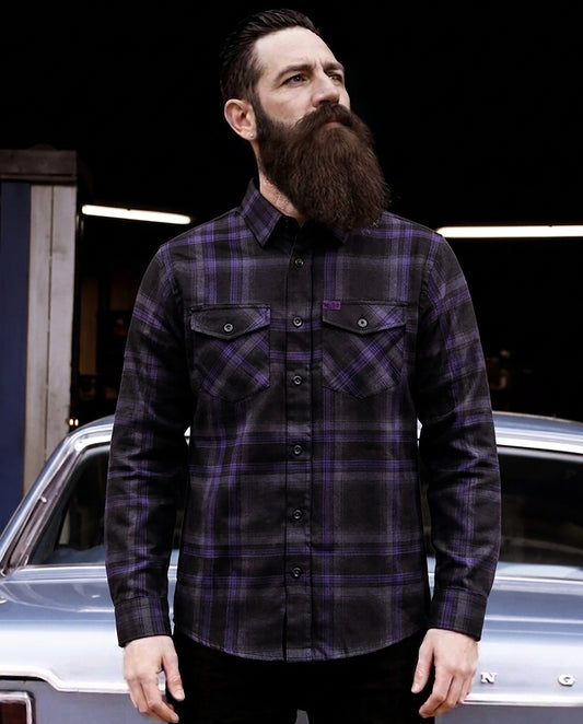 Man wearing a black and purple plaid flannel shirt - purple flannel- standing in front of a car - Kiss the Sky Flannel by Greasy Hands Society