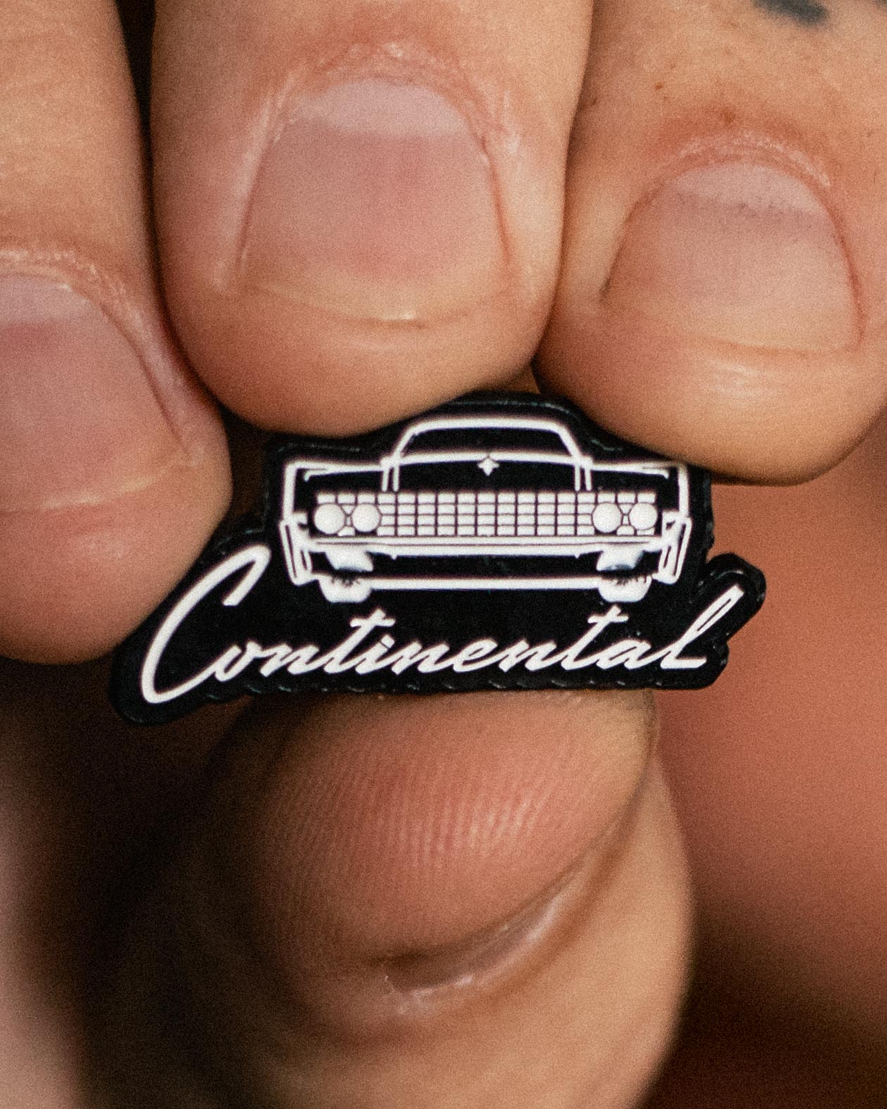 lincoln Continental Pin black and white enamel pin held up for you to see