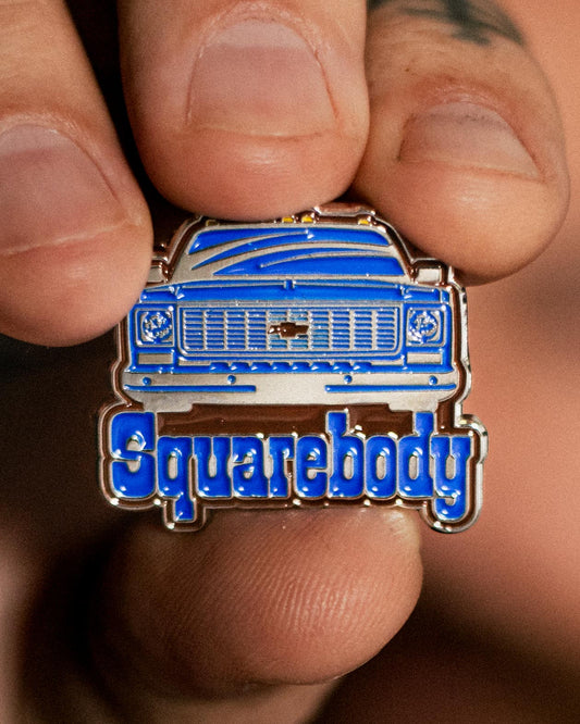 chevy squarebody pin blue, white and brown enamel pin being held up so you can see it
